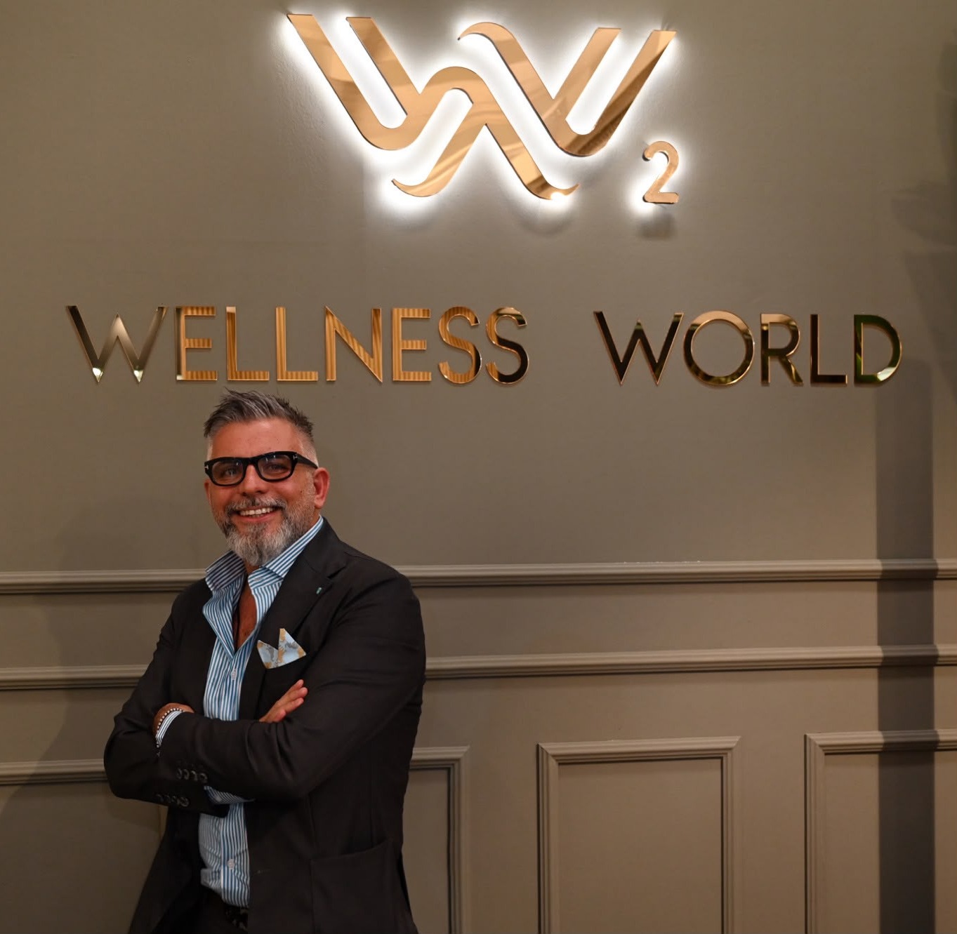 Il titolare di Wellness World davanti alla parete con il logo WW²